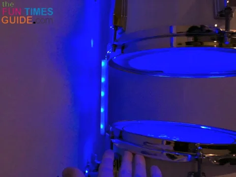 A closeup of the cord hider between 2 drums on the wall, with the exposed LED lights facing the wall.