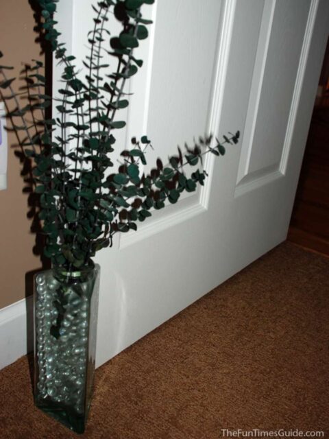 Large, uniquely shaped glass bottles and jars make great door stops! This one is filled with clear decorative marbles and eucalyptus leaves - a natural room deodorizer! 