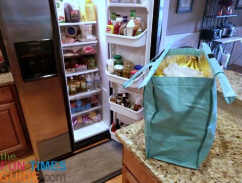 Putting items from the insulated Lotus reusable shopping bag into the refrigerator, one by one.