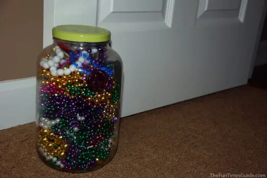A large pickle jar filled with Mardi Gras beads and used as a door stop. 