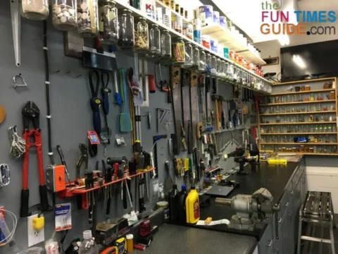 An organized garage workspace with everything in its place and a DIY shelf organizer made from glass jars and lids.