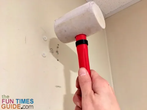 Using a rubber mallet to get the drywall toggle anchors flush with the wall.